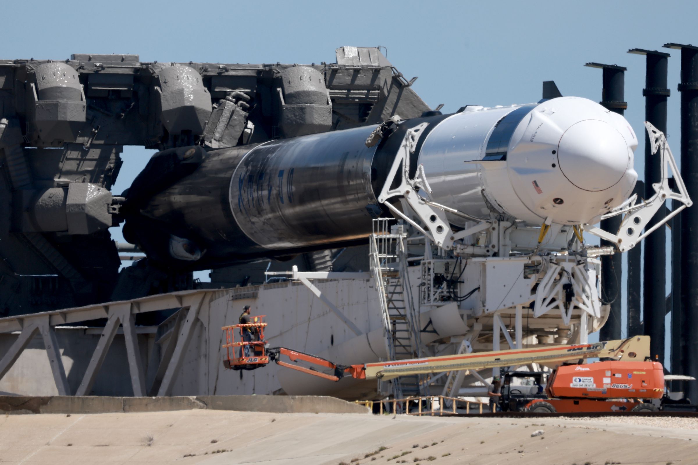 A Falcon 9 rocket, turned sideways while workers prepare it for a new mission.