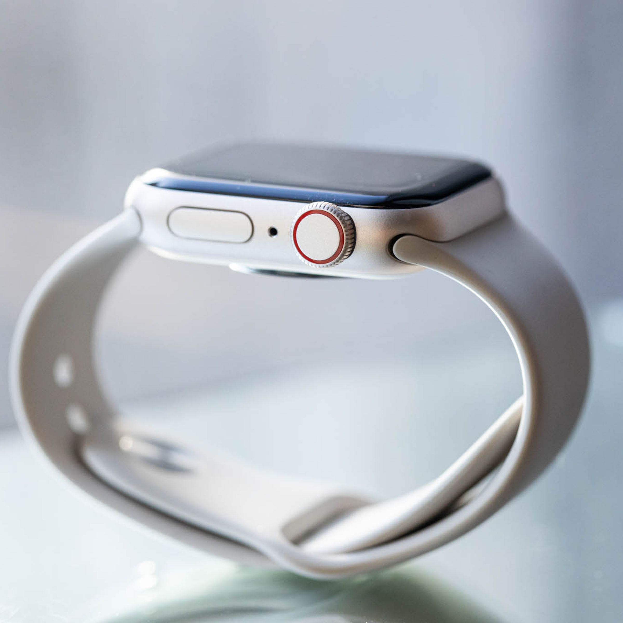 A picture of an Apple Watch SE balanced on its silicone band.