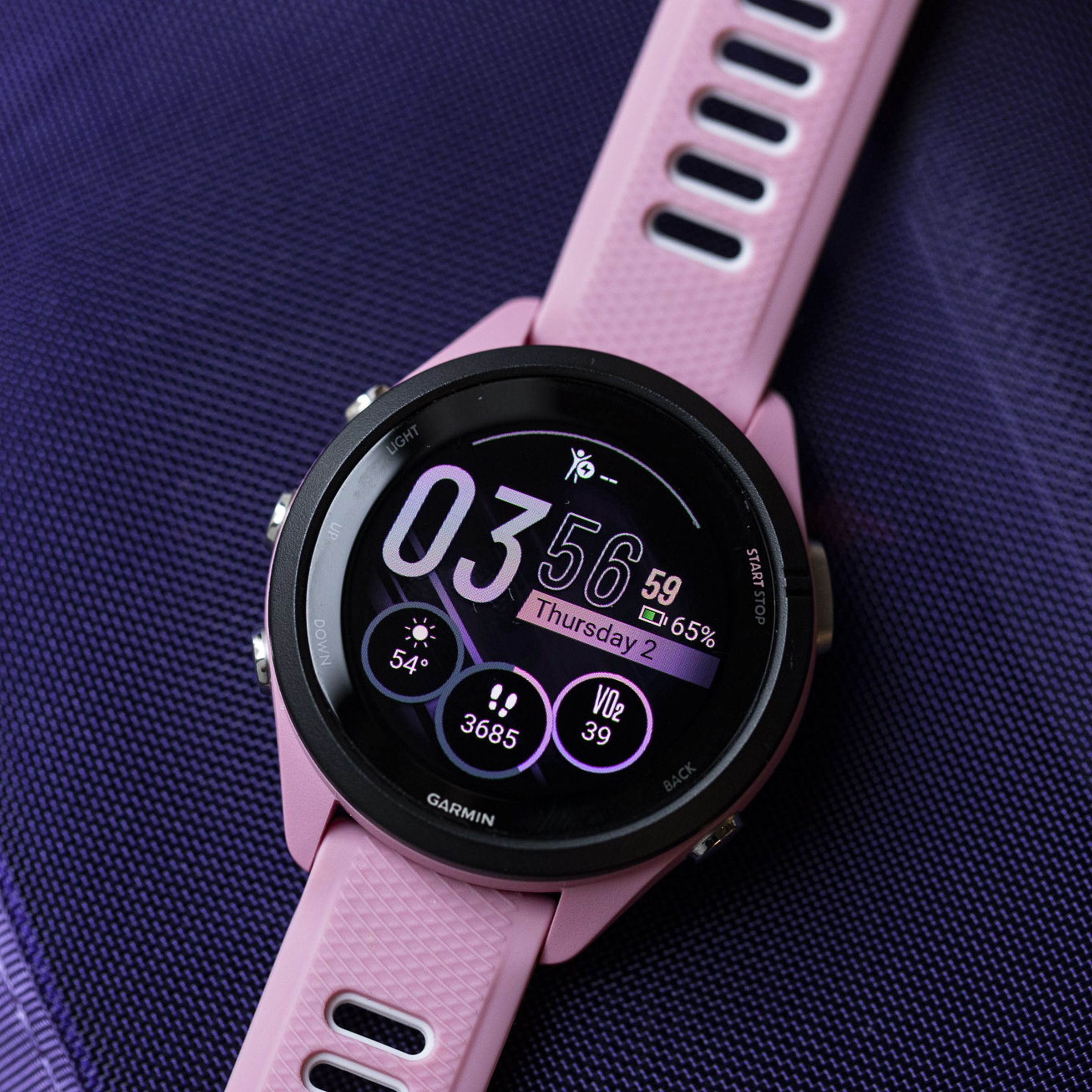 Close-up of the Garmin Forerunner 265S’s OLED display and watchface on a purple background