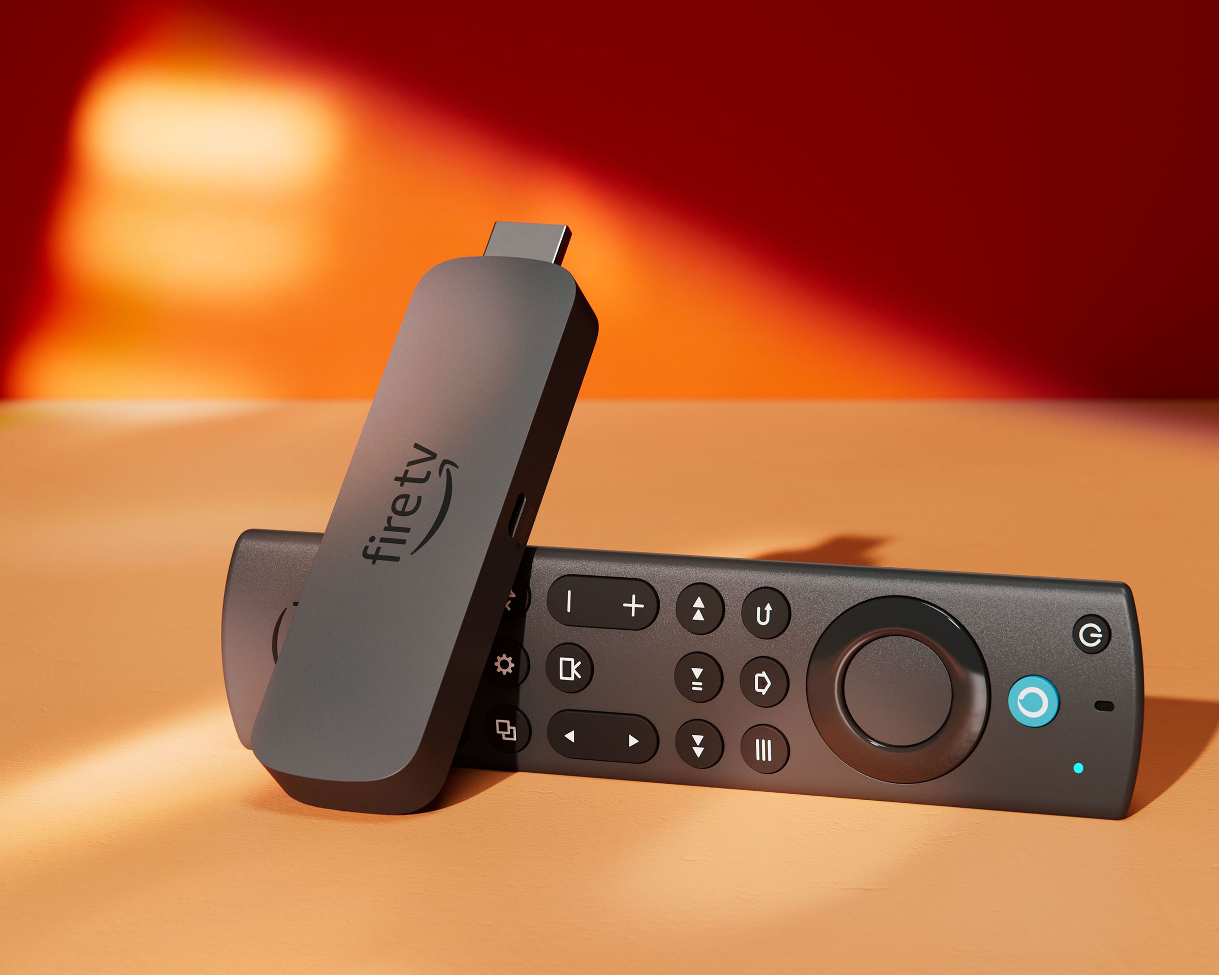 A close-up photo of the Amazon Fire TV Stick 4K Max resting on its side on a table against a red wall.