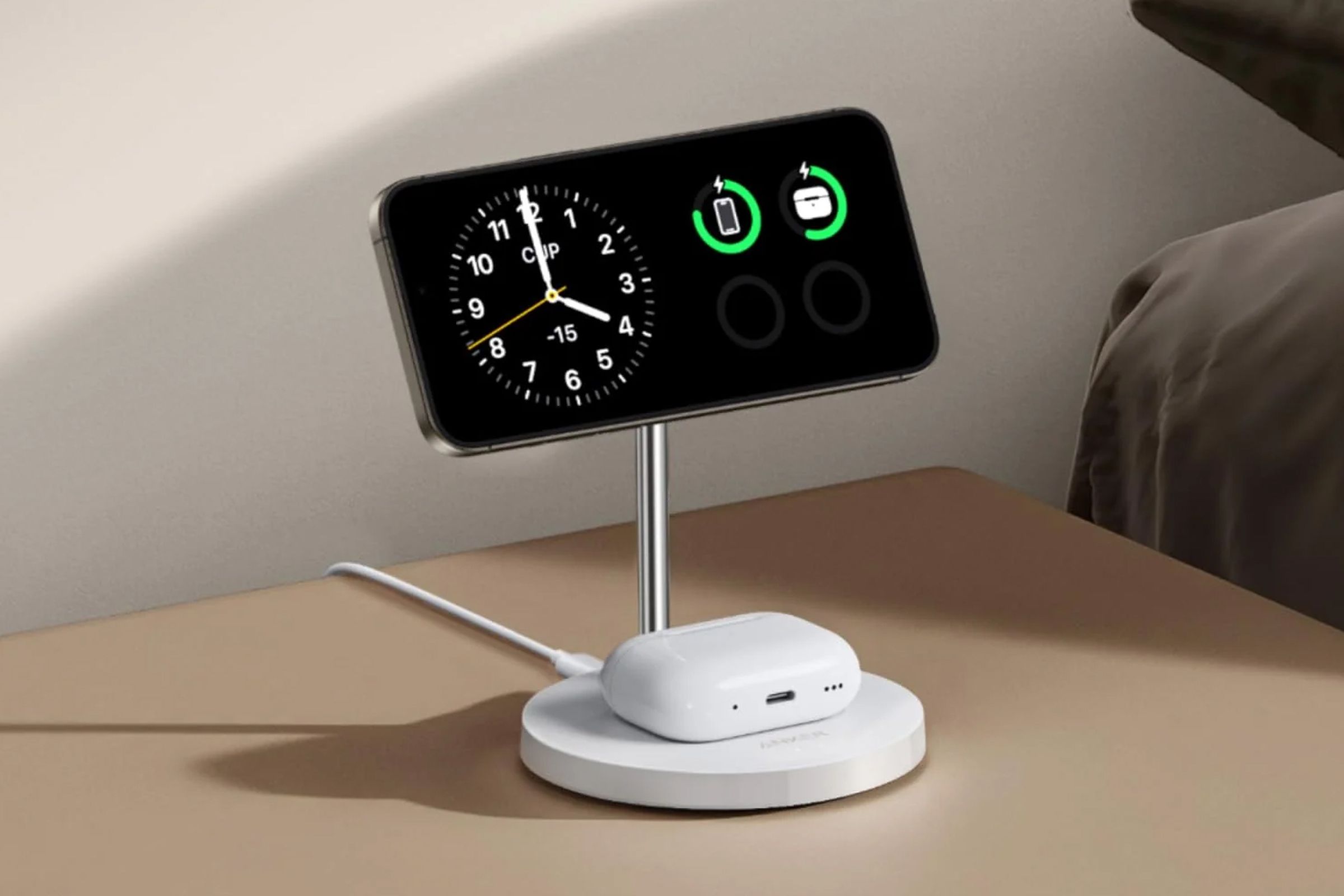 A tilted close-up image of Anker’s white MagGo Wireless Charger with a pair of AirPods on the bottom and an iPhone showing StandBy mode on the top.