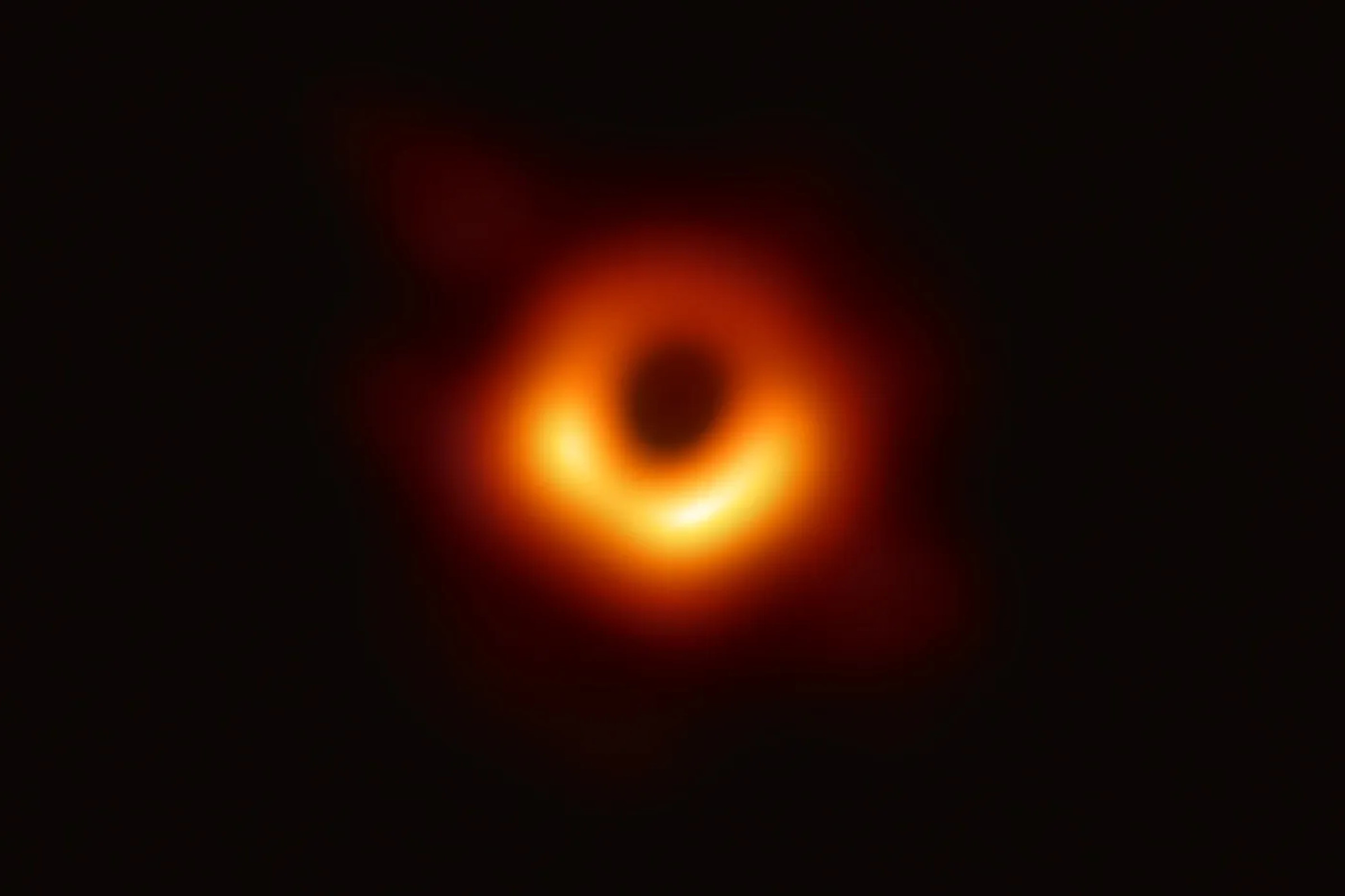 The first image of a black hole — a fuzzy, orange and red ring against a black backdrop.