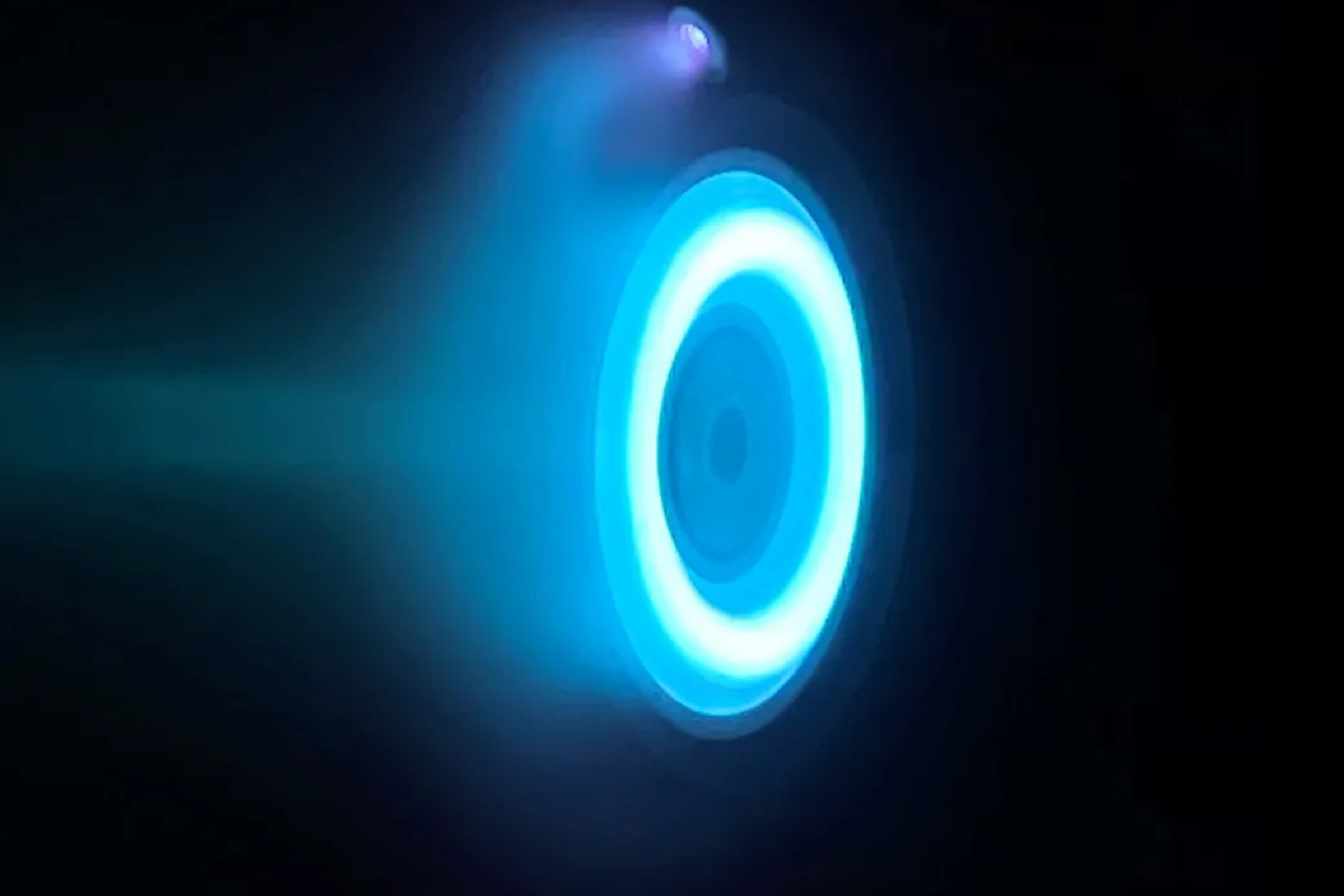 The glowing blue ring of an electric Hall thruster. in an otherwise black image.